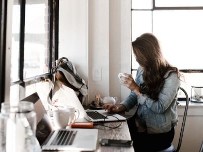 woman holds a cup of coffee while working